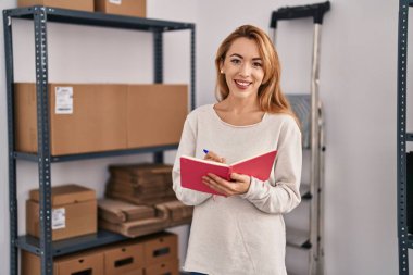 Genç kadın ecommerce busines işçisi ofisteki deftere yazıyor.