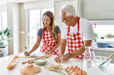 Orta yaşlı İspanyol çift gülümseyerek mutfakta mutlu ekmek pişiriyor..