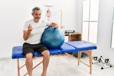 Orta yaşlı İspanyol bir adam, ağrı kesici kliniğinde elinde pilates topu, elleriyle para hareketi yapıyor, maaşını istiyor, milyonerlik işi yapıyor. 