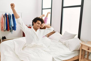 Genç çift yatak odasındaki yatakta uzanıyor ve esniyor..
