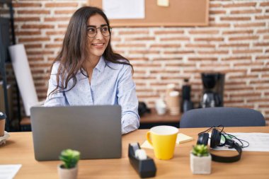 Ofiste çalışan genç İspanyol iş kadını laptopu kullanıyor.