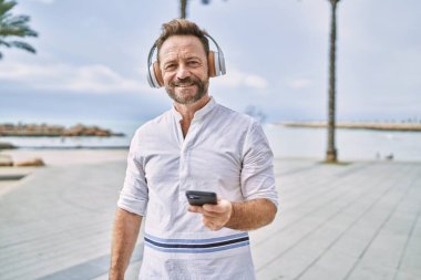 Deniz kenarında akıllı telefon kullanan orta yaşlı bir adam.