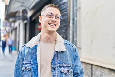 Young hispanic man smiling confident looking to the side at street