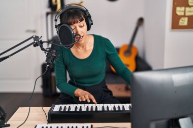 Genç, güzel, İspanyol bir müzisyen müzik stüdyosunda piyano çalıyor.