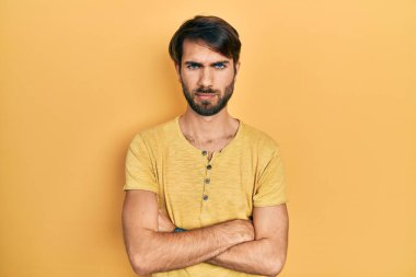 Gündelik kıyafetler giyen, kuşkucu ve gergin genç İspanyol bir adam. Yüzünde çapraz kollarla onaylamayan bir ifade var. negatif kişi. 