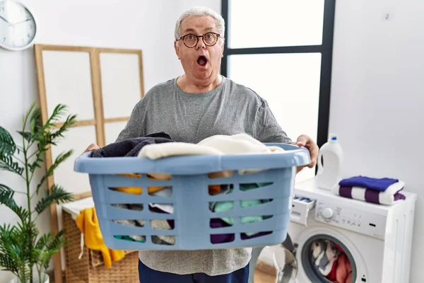 Senior Caucasian Man Holding Detergent Bottle Laundry Room Shock Face — Stock Photo, Image