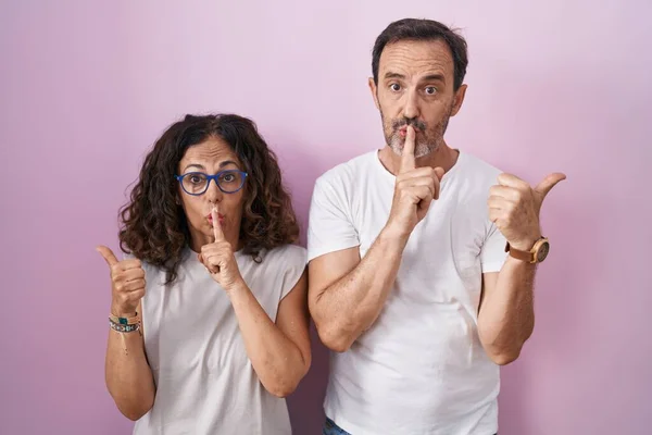 Middle Age Hispanic Couple Together Pink Background Asking Quiet Finger — Stok fotoğraf