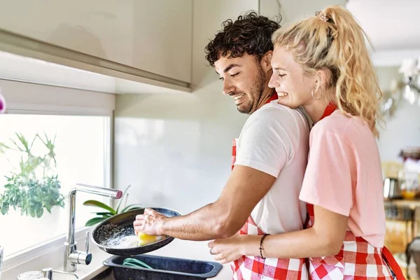 Giovane Coppia Sorridente Felice Abbracciando Piatti Lavaggio Cucina — Foto Stock