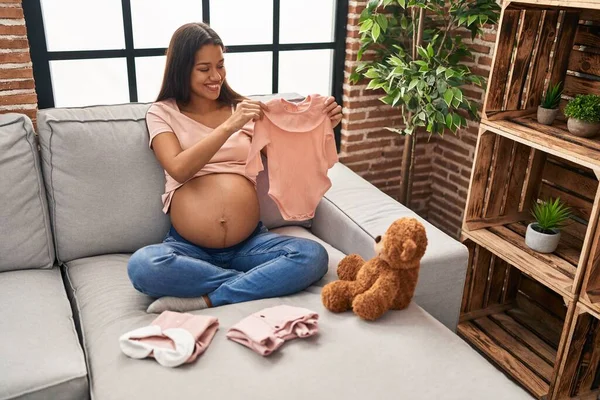 Mujer Latina Joven Embarazada Sosteniendo Ropa Bebé Casa — Foto de Stock