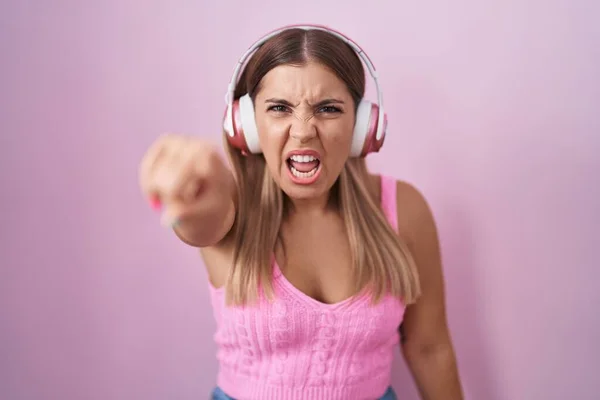 年轻的金发女人用耳机听音乐 对着摄像机不悦 对你怒气冲冲 — 图库照片
