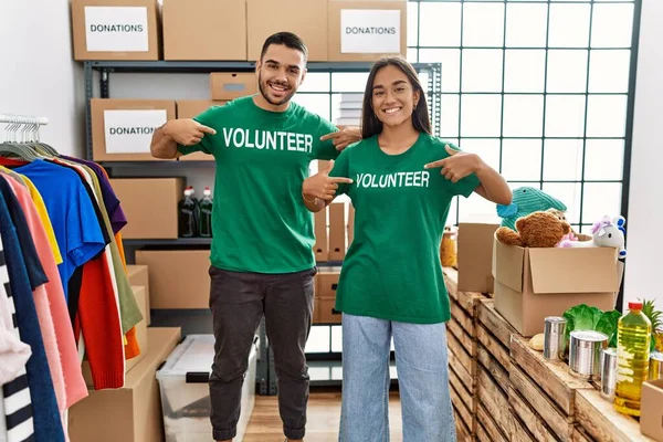 Young Latin Couple Smiling Happy Pointing Volunteer Uniform Charity Center — Stock Photo, Image