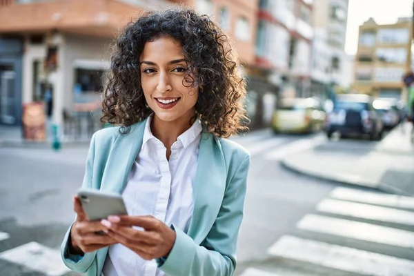 プロの笑顔を身に着けている若いヒスパニック系ビジネス女性は スマートフォンを使用して街で自信を持って笑顔 — ストック写真