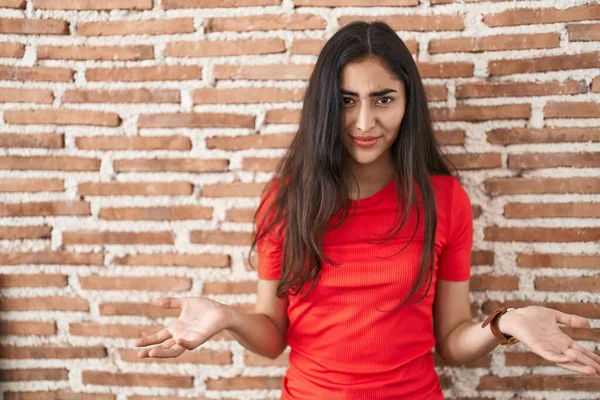 年轻的少女站在砖墙上 毫无头绪 与张开的双臂混淆不清 没有概念 — 图库照片
