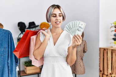 Genç Kafkas müşteri kadın elbise mağazasında alışveriş torbaları ve dolar tutuyor..