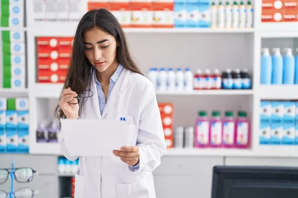 Young Hispanic Girl Pharmacist Reading Prescription Pharmacy — Stok fotoğraf