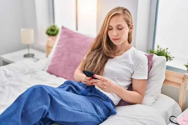 Mujer Rubia Joven Usando Teléfono Inteligente Cama Relajado Con Expresión — Foto de Stock