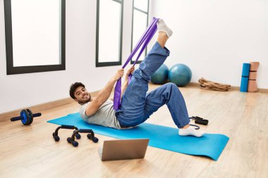 Spor salonunda online spor dersi aldığı için mutlu gülümseyen İspanyol genç adam..