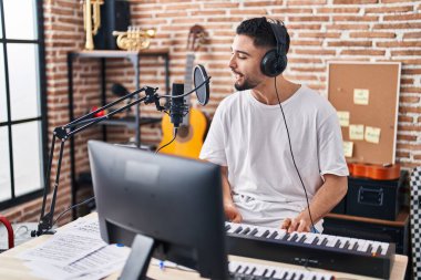 Genç Arap müzisyen müzik stüdyosunda piyano klavyesi çalıyor.
