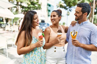 Üç İspanyol arkadaş gülerek şehirde dondurma yiyor..