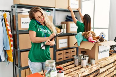 Yardım merkezinde çalışmaktan mutlu gülümseyen iki genç gönüllü kadın. Gülümseyen mutlu bir kız akıllı telefonda konuşuyor..