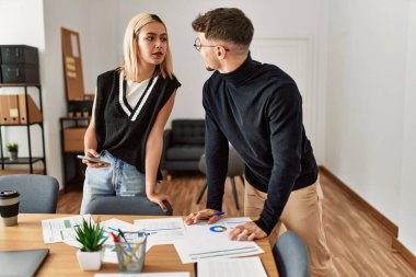 Ofiste çalışan akıllı telefon kullanan iki ciddi yüzlü iş adamı..