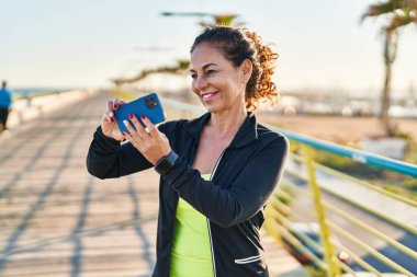 Orta yaşlı İspanyol kadın gezinti güvertesinde selfie çekiyor.