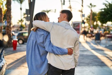 Genç adam ve kadın çift sokakta birbirlerine sarılıyorlar.