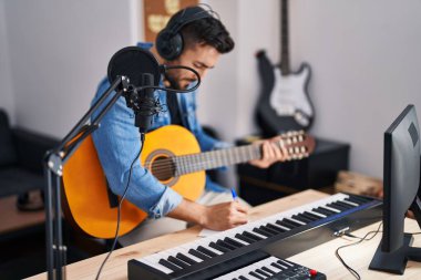 Genç İspanyol bir adam müzik stüdyosunda klasik gitar çalarak şarkı söylüyor.