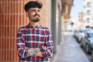 Genç İspanyol adam gülümsüyor. Kendine güveni tam. Sokakta çapraz hareketlerle duruyor.