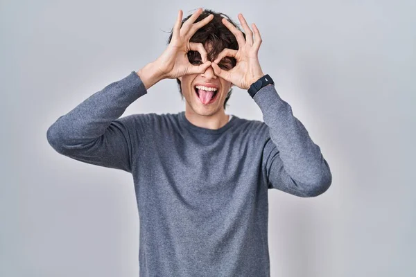 Joven Parado Sobre Fondo Aislado Haciendo Buen Gesto Como Binoculares — Foto de Stock