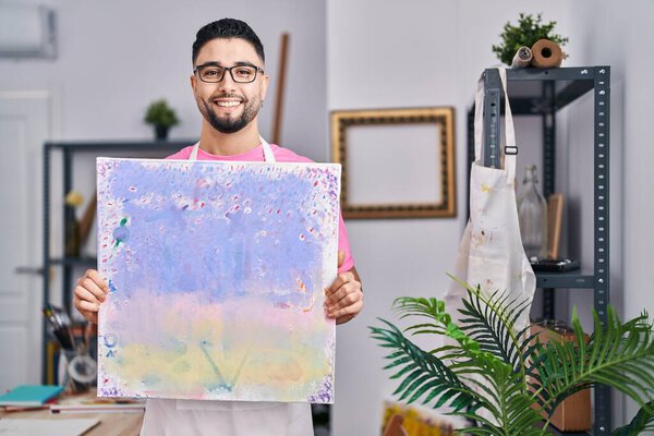 Young arab man artist smiling confident holding draw at art studio