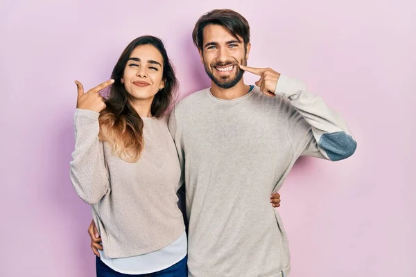 若いヒスパニック系のカップルのカジュアルな服を笑顔を見せ 指の歯と口で指して着ている 歯の健康の概念 — ストック写真