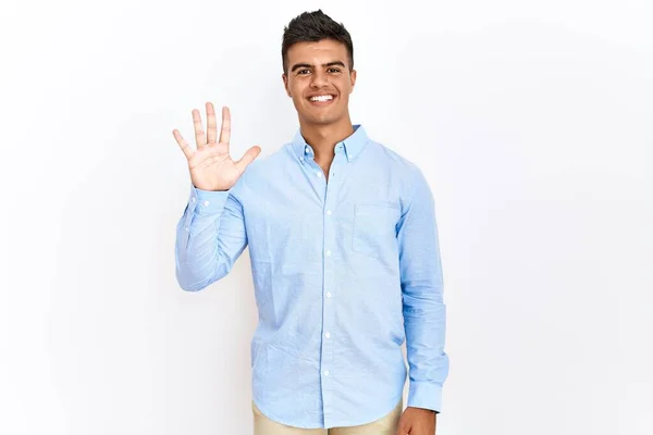 自信と幸せ笑顔ながら 孤立した背景を示すと指の数5で指摘しながら ビジネスシャツを着て若いヒスパニック系の男 — ストック写真