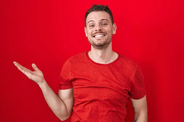 Kırmızı Arka Planda Duran Genç Spanyol Adam Mutlu Bir Şekilde — Stok fotoğraf