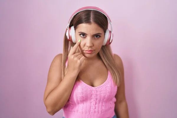 Young Blonde Woman Listening Music Using Headphones Pointing Eye Watching — Foto de Stock