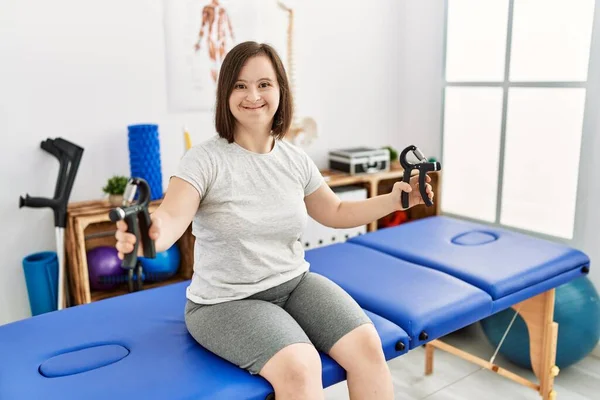 Brunette woman with down syndrome using hand grip at physiotherapy clinic