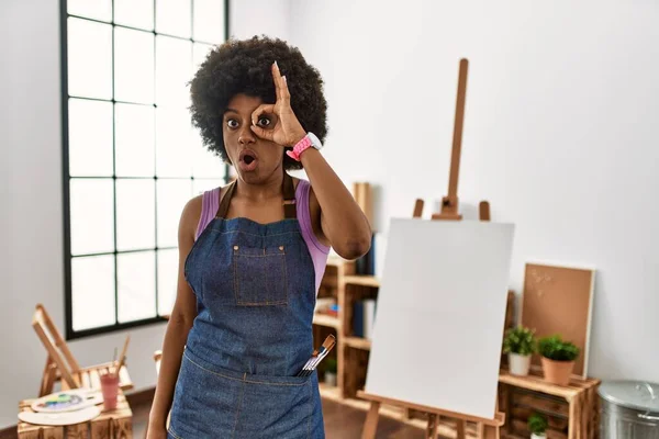 アフリカ系アメリカ人の若い女性がアートスタジオで 驚きの顔 目を指で見てショックを受けたOkジェスチャーをしています 信じられない表現 — ストック写真