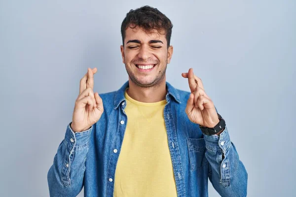 Joven Hombre Hispano Pie Sobre Fondo Azul Gesto Dedo Cruzó — Foto de Stock