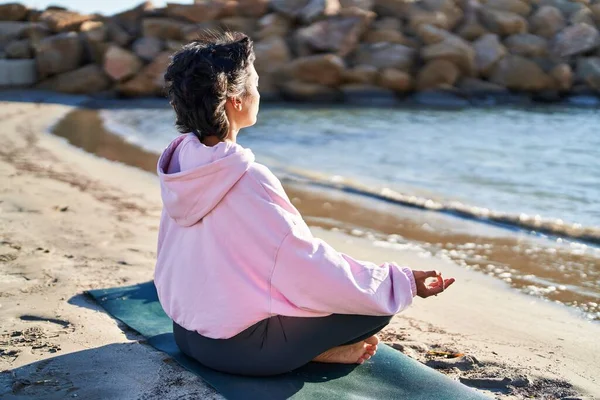 年轻女子坐在海滨沙滩上练习瑜伽 — 图库照片
