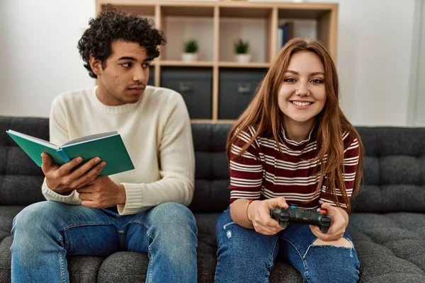 Vrouw Spelen Video Game Terwijl Ongelukkige Vriend Boek Lezen Thuis — Stockfoto