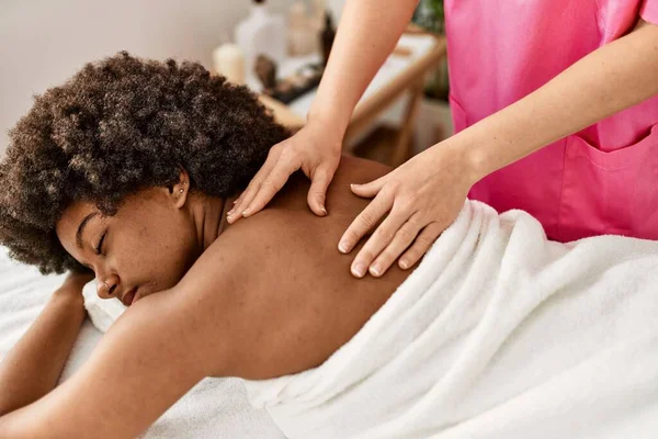 Young african american woman having back massage at beauty center