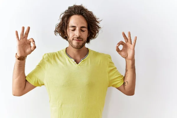 年轻的惊慌失措的男人站在孤立的背景上放松 闭上双眼微笑 用手指做冥想手势 瑜伽概念 — 图库照片