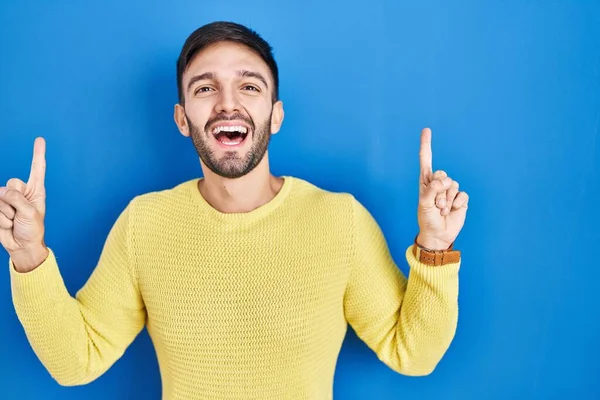 Homem Hispânico Sobre Fundo Azul Sorrindo Espantado Surpreso Apontando Para — Fotografia de Stock