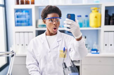 Afrika kökenli Amerikalı bir kadın bilim adamının laboratuarında çalışıyor. Akıllı telefonuyla video görüşmesi yapıyor. Şaşırmak için ağzı açık kalmış ve korkmuş. 