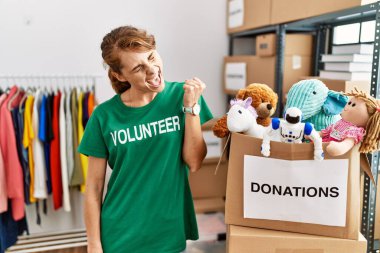 Bağışta gönüllü tişört giyen beyaz güzel bir kadın kolları havada, gülümseyen ve başarı için bağıran kazanan jestler yaparak çok mutlu ve heyecanlı duruyor. kutlama konsepti. 