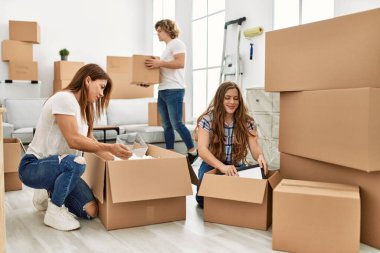 Anne ve çift evde karton paketleri açarak gülümsüyor.