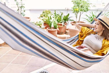 Balkonda hamakta uzanmış yaz şapkası takan İspanyol genç kız..