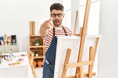 Sanat stüdyosundaki Arap genç adam kameraya kızgın ve sinirli bir şekilde seni işaret ediyor. 