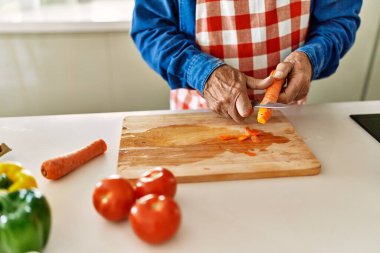 Kıdemli adam mutfakta havuç kesiyor.