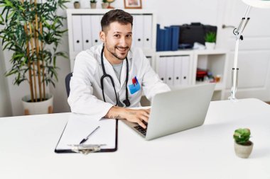 Klinikte çalışan doktor üniforması giyen genç İspanyol adam.